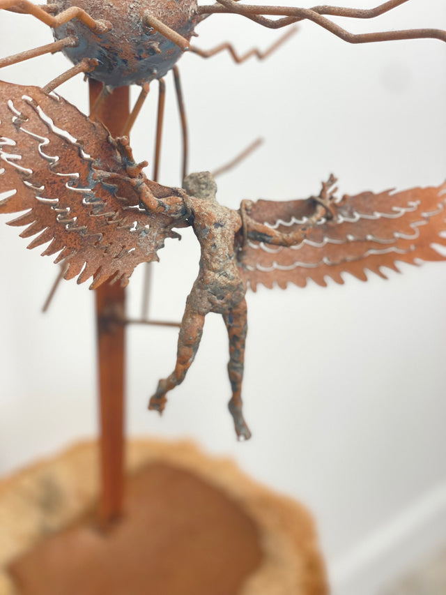 Brutalist iron sculpture of Icarus with wings flying near sun rays